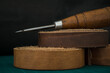 Closeup shot of a wooden stitching awl and genuine leather rolls on a craftsman's work table