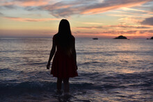 Woman In Dress Walking Away To Sea On Sunset