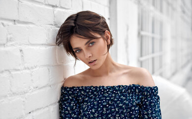 Beauty portrait of female face with natural clean skin and short hair on white wall