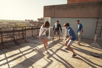 Wall Mural - People having fun playing football on building rooftop terrace
