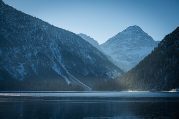 Wall Mural - sun light shines in the evening between the mountains at plansee in winter