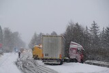 Fototapeta  - An accident on the road involving a truck in very difficult winter conditions. Roadside assistance during an accident.
