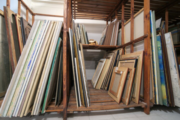 Wooden shelves at art gallery storage full of pictures and art equipment