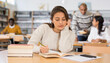 © JackF - Focused young hispanic woman engaged in research, looking for information in books in public library
