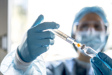 Wall Mural - Medical worker holding the Covid-19 vaccine with a syringe