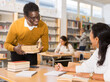 © JackF - Polite friendly african american librarian helping woman find necessary information, giving her books..