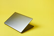 Grey silver laptop isolated on a yallow background. Top view with copy space, flay lay.