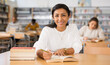 © JackF - Portrait fo cheerful adult hispanic woman engaged in self-education, reading books in public library