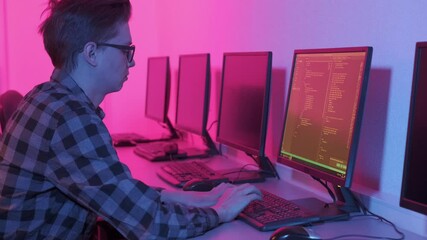 Programming. A man in glasses for vision and a shirt, working on a computer in IT writes codes. Programmer typing data code on the keyboard.