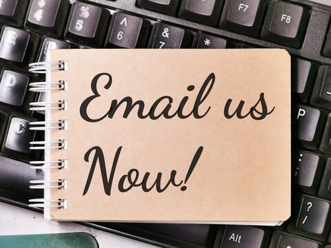 Text EMAIL US NOW written on brown paper note on computer keyboard.Business concept.