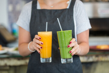 Closeup shot of waitress serving freshly made avocado and mango juices at cafe restaurant