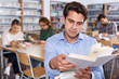 © JackF - Portrait of focused intelligent man browsing books while visiting public library..