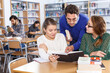 © JackF - Male tutor helping girls preparing for exam in university classroom..