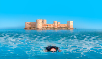 Wall Mural - Beautiful girl is swimming underwater, The Mersin castle in the background - Mersin, Turkey 