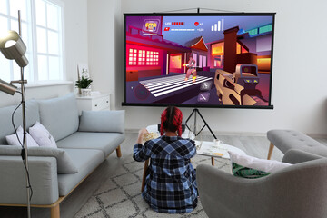 Wall Mural - Young woman playing video games on big screen at home