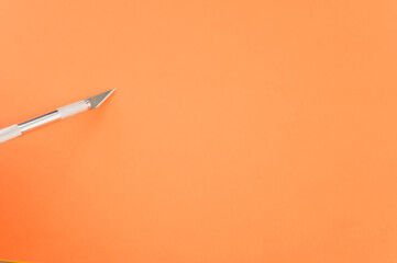 Poster - Closeup shot of metallic scalpel isolated on orange background