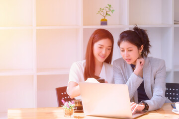 Two young girl enjoy working using laptop computer on the table.