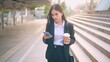 © tonefotografia - A young business woman wearing black suit is using smart phone , holding a cup of coffee in the city, Business Lifestyle Concept