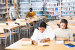 © JackF - Positive young women preparing to exam in library, reading books and writing in notepads