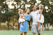 © Алина Битта - Parents hold daughters in their arms In Countryside, enjoing time together. Happy family concept. Blurred trees background.