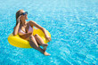 © F8  \ Suport Ukraine - Young woman with perfect sexy body in bikini and glamorous sunglasses, posing on an inflatable yellow ring in the swimming pool outdoors