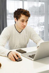 Wall Mural - A man working on a laptop at home at bright kitchen