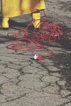 Low Section Of Man Standing With Red Cable On Street