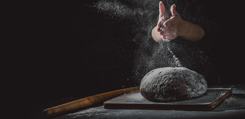 woman chef hand clap with splash of white flour and black background with copy space. woman's hands Making bread