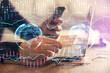 © peshkova - Double exposure of man's hands holding and using a phone and financial graph drawing. Analysis concept.