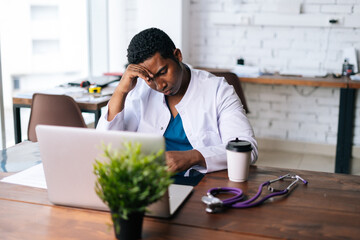 Poster - African American black man doctor is analyzing history disease of patient using MRI brain head scan image while working at desk, working on laptop. Concept of medicine and health care.