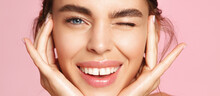 Skincare And Beauty. Close Up Of Smiling Young Woman Winking At Camera, Touching Shiny Healthy Skin, Nourished Face After Tea Tree And Lemon Facial Serum And Moisturizer, Pink Background