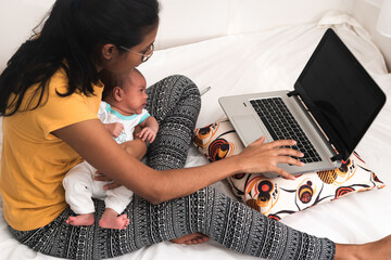 Young Hispanic mother with a baby working from home