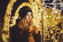 Girl With A Garland Of Light Bulbs On The Background Of Night Lights. Festive Lighting Of The City