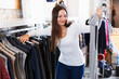 Adult smiling female choosing fashion sweater in the boutique..