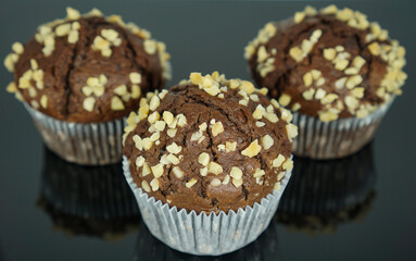 three chocolate muffins in front of a black background	
