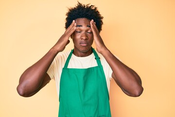 Poster - Handsome african american man with afro hair wearing waiter apron suffering from headache desperate and stressed because pain and migraine. hands on head.