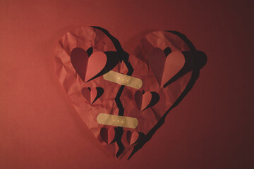 The idea of ​​mending the broken heart. red heart filled with tiny hearts sticking with band-aid on top.