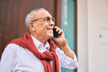 Wall Mural - senior man smiling happy talking on the smartphone standing at new home.