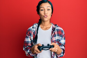 Wall Mural - Beautiful hispanic woman playing video game holding controller looking at the camera blowing a kiss being lovely and sexy. love expression.