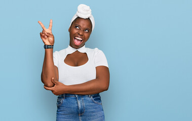 Poster - Young african woman with turban wearing hair turban over isolated background smiling with happy face winking at the camera doing victory sign with fingers. number two.