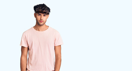 Wall Mural - Young hispanic man wearing casual clothes with serious expression on face. simple and natural looking at the camera.