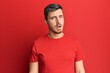 © Krakenimages.com - Handsome caucasian man wearing casual red tshirt in shock face, looking skeptical and sarcastic, surprised with open mouth
