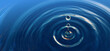Clear blue water drop with rings and small waves.