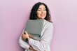 © Krakenimages.com - Young brunette woman with curly hair hugging laptop with love winking looking at the camera with sexy expression, cheerful and happy face.
