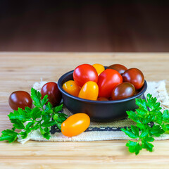 Wall Mural - Red, Yellow, Orange Grape Tomatoes in Bronze Bowl on Wooden Table