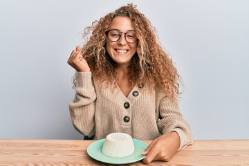 Poster - Beautiful caucasian teenager girl eating fresh white cheese screaming proud, celebrating victory and success very excited with raised arm