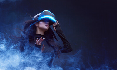 Wall Mural - beautiful woman with flowing hair in futuristic dress over dark background. girl in glasses of virtu