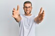 © Krakenimages.com - Young caucasian man wearing casual clothes and glasses looking at the camera smiling with open arms for hug. cheerful expression embracing happiness.