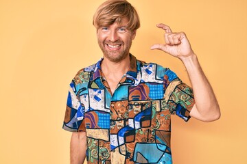 Sticker - Young blond man wearing summer shirt smiling and confident gesturing with hand doing small size sign with fingers looking and the camera. measure concept.