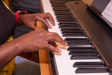 Black woman plays the piano in her living room